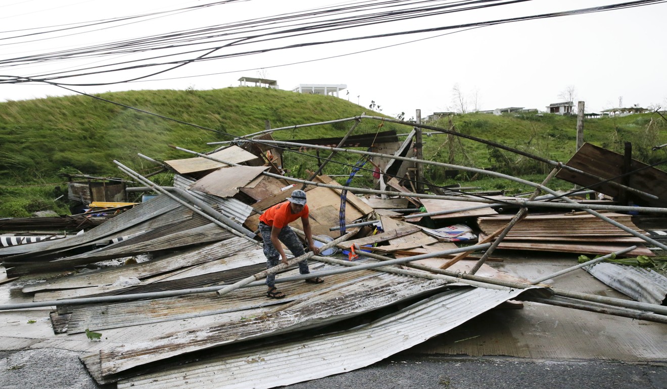 A government worker picks up pieces from a structure destroyed by strong winds. Photo: AP