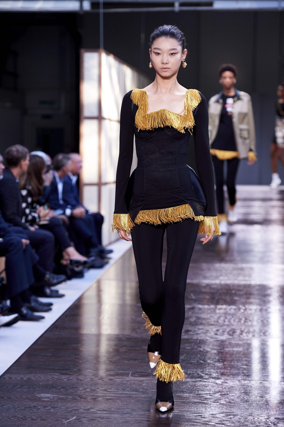 A model presents an eye-catching black outfit with edges decorated with gold tassels from Burberry’s spring-summer 2019 collection at London Fashion Week. Photo: AFPl