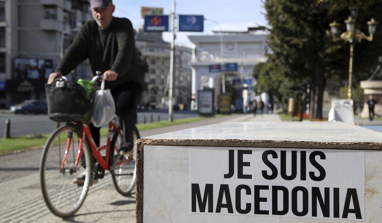 A man passes a sign that reads in French: ‘I am Macedonia’ written by opponents of the referendum in Skopje. Photo: AP