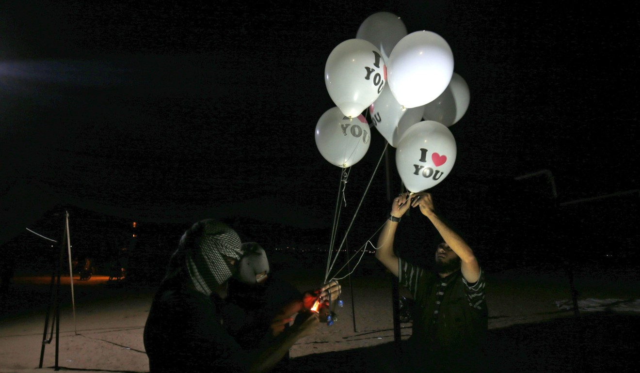 Masked Palestinian protester hold incendiary devices attached to balloons to be flown towards Israel. Photo: AFP