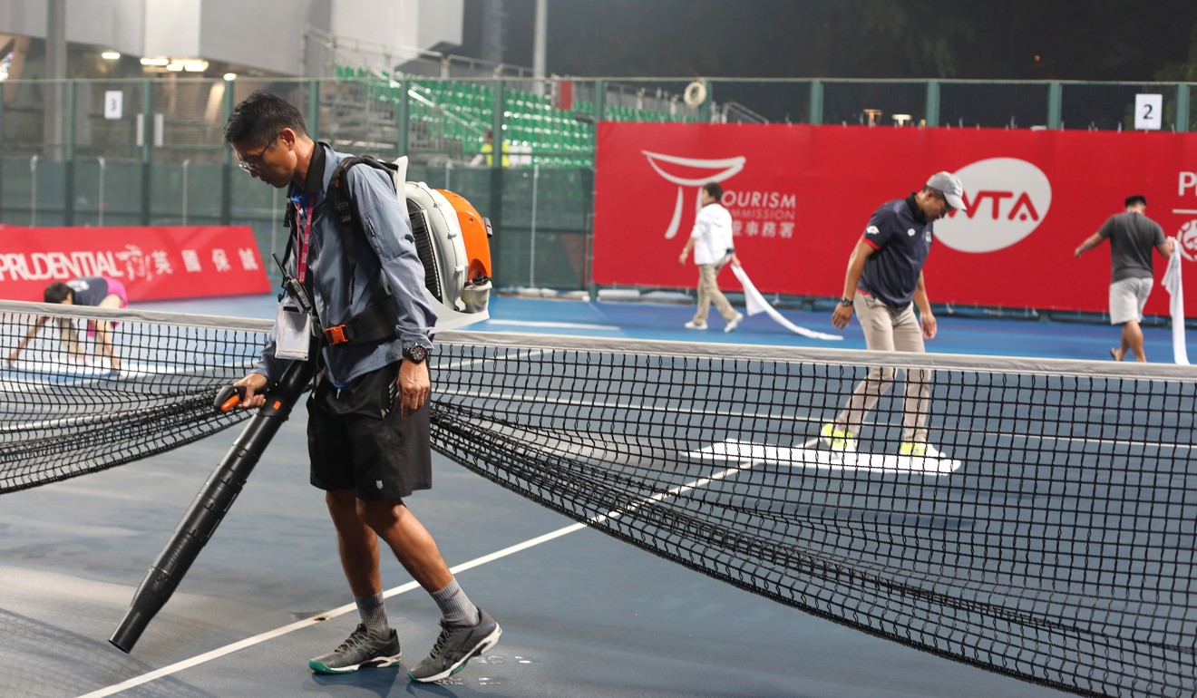 Tournament staff member Eric Chung blows Court Two dry.