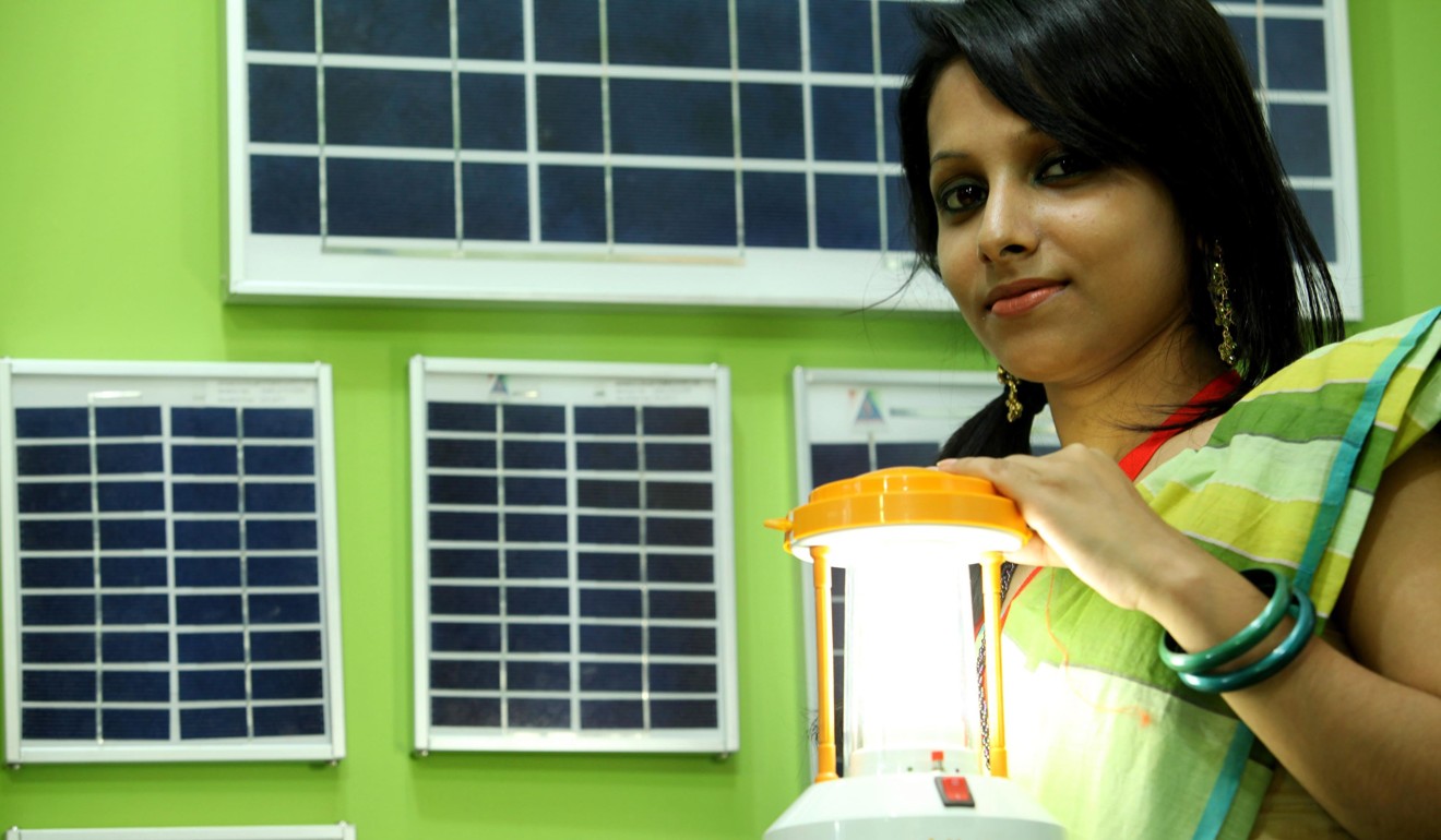 A sales girl shows a lamp run on solar energy in Dhaka, Bangladesh. Photo: EPA