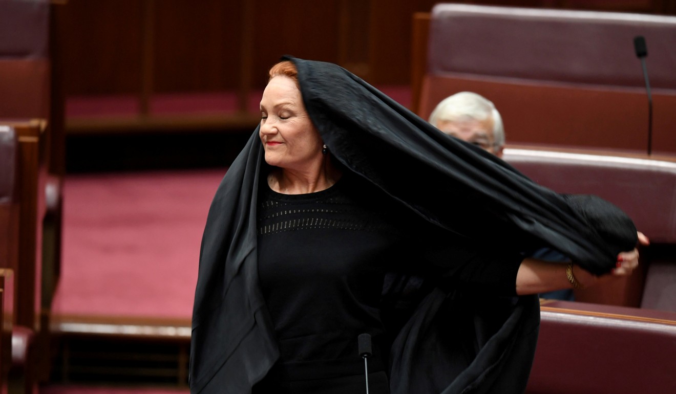 Australian One Nation party leader Senator Pauline Hanson pulls off a burka in the Senate chamber at Parliament House in Canberra. Photo: Reuters