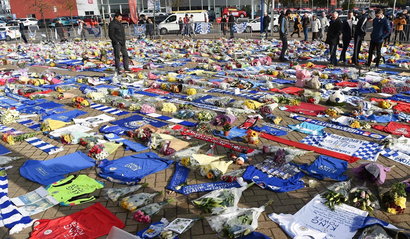 People pause at the tributes gathered outside the King Power Stadium in honour and remembrance of those who died in Saturday’s helicopter crash. Photo: AFP