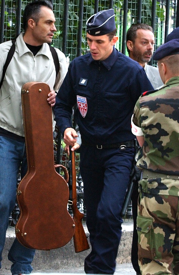 Plainclothed and uniformed police hold a rifle after an unidentified man pulled it out of a guitar case just after President Jacques Chirac passed by on July 14, 2002. Photo: Reuters