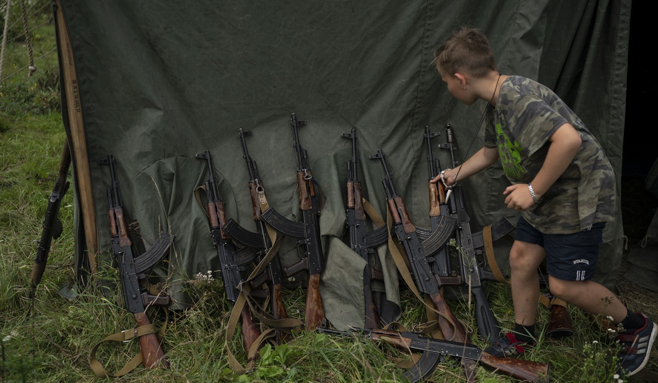 A young participant of the summer camp grabs an AK-47 during a tactical exercise. Photo: AP