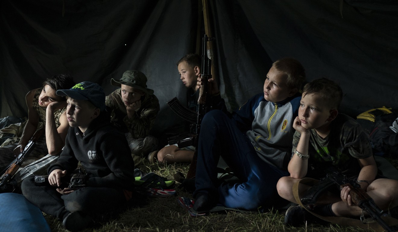 Young participants sit inside a tent with their AK-47s as they receive instructions. Photo: AP