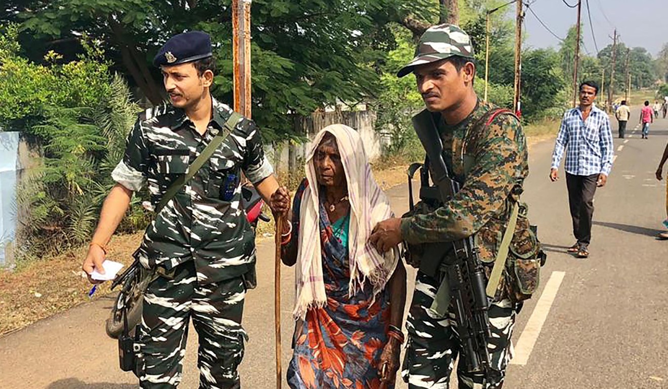 Security personnel assist an elderly woman near a polling station in Sukma, Chhattisgarh state on Monday. Photo: AFP