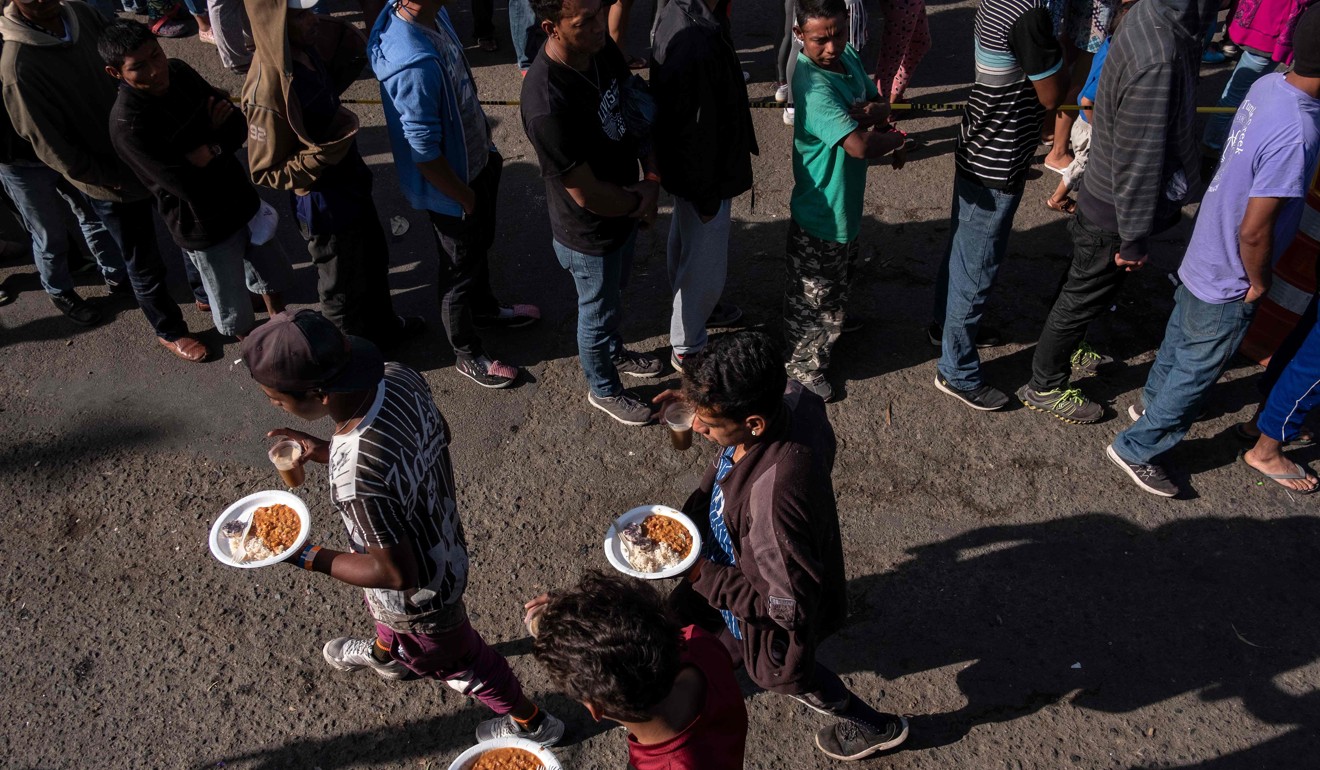A group of Central American migrants – mostly from Honduras – moving towards the US, line up for food outside a temporary shelter at the US-Mexico border in Tijuana. Photo: AFP