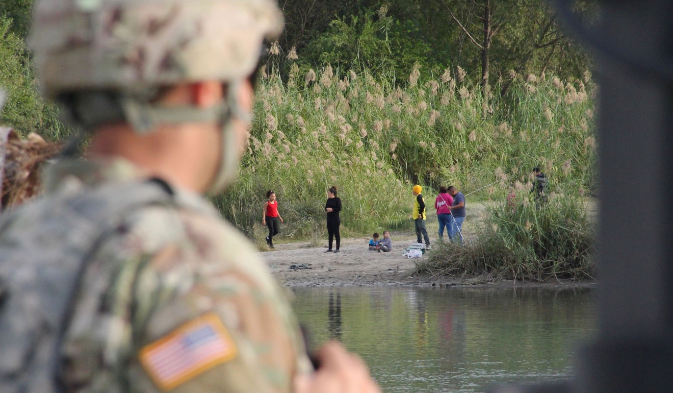 A US soldier looks across the Rio Grande from Laredo, Texas, into Nuevo Laredo, Mexico, where a group of people hang out on the river bank on November 17. Photo: AFP
