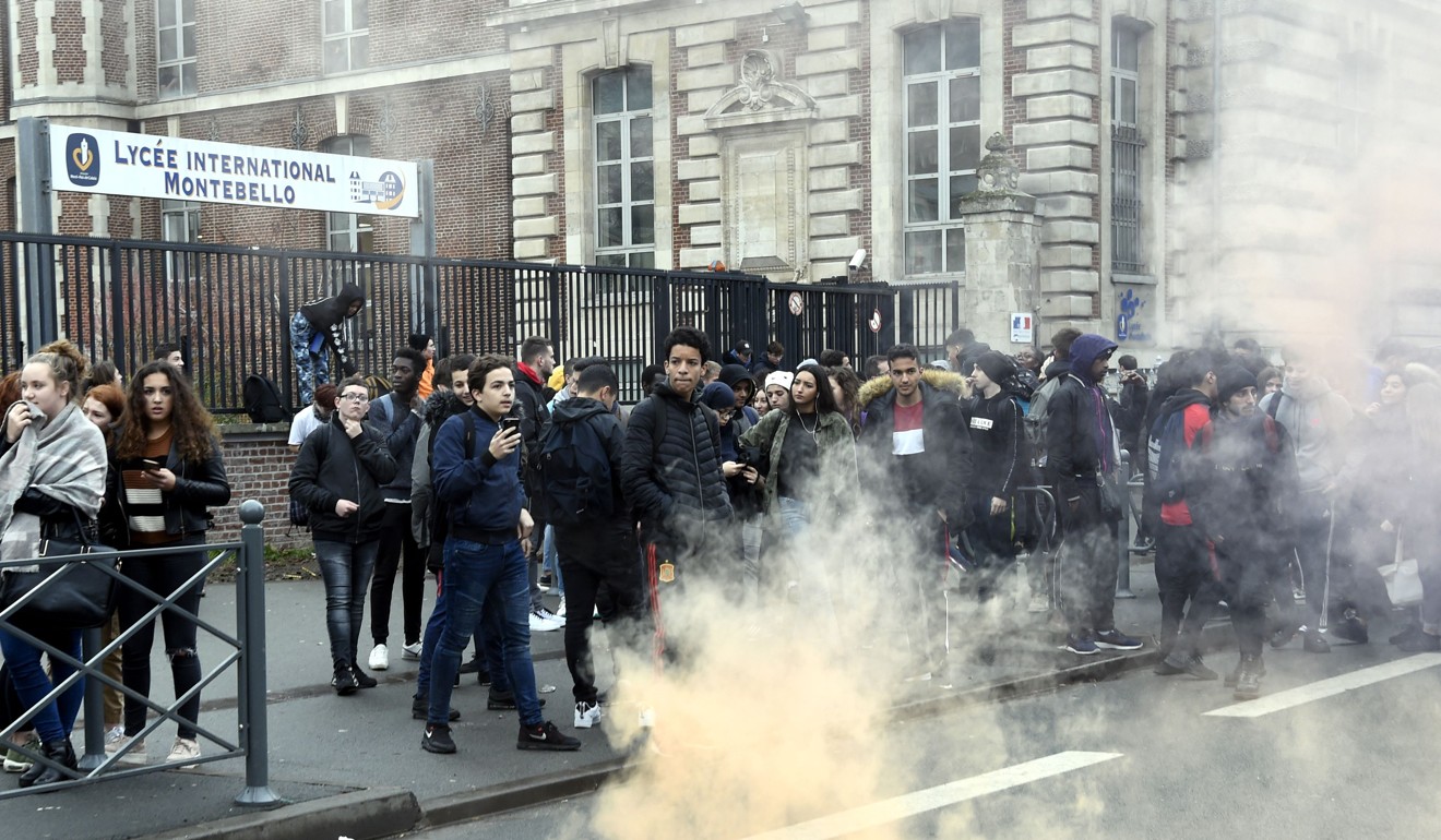 High school students stand amid smoke during a demonstration in front of the lycee Montebello of Lille. Photo: AFP