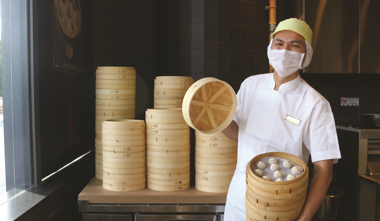 A chef lifts the lid on some cooked Din Tai Fung dumplings.