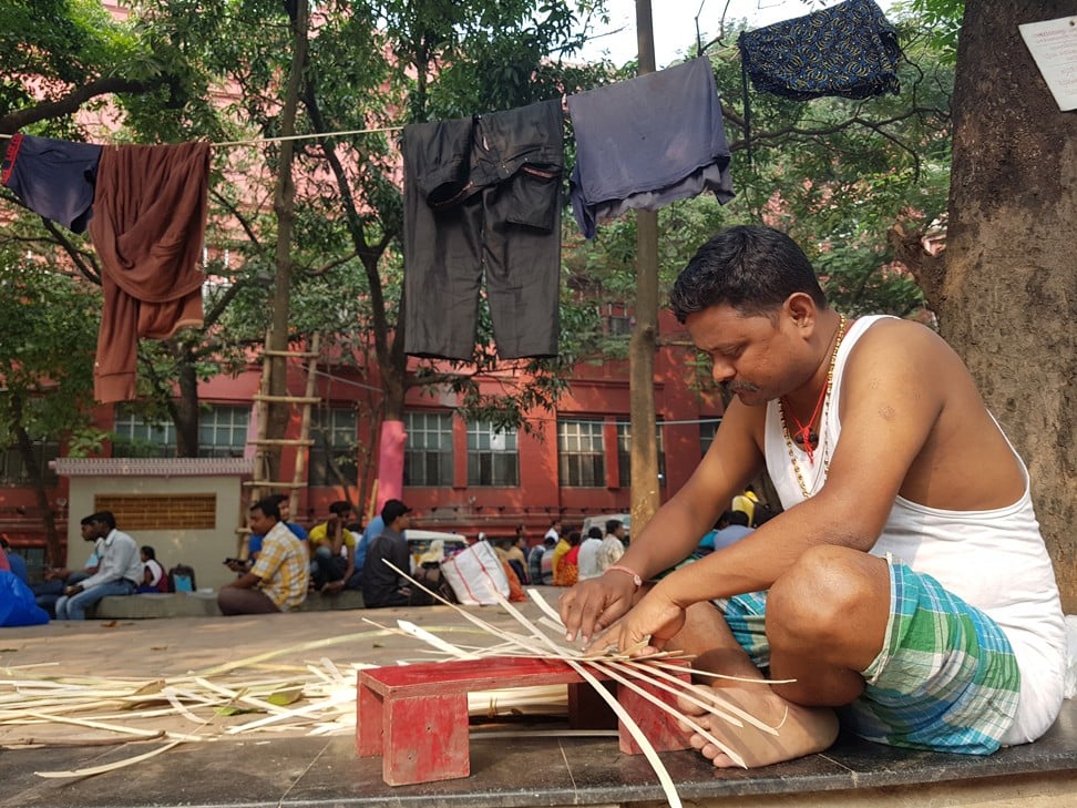 Sanjay Mallick weaves bamboo adeptly in a criss-cross pattern to make a tray in front ofthe morgue. Photo: Sohini C