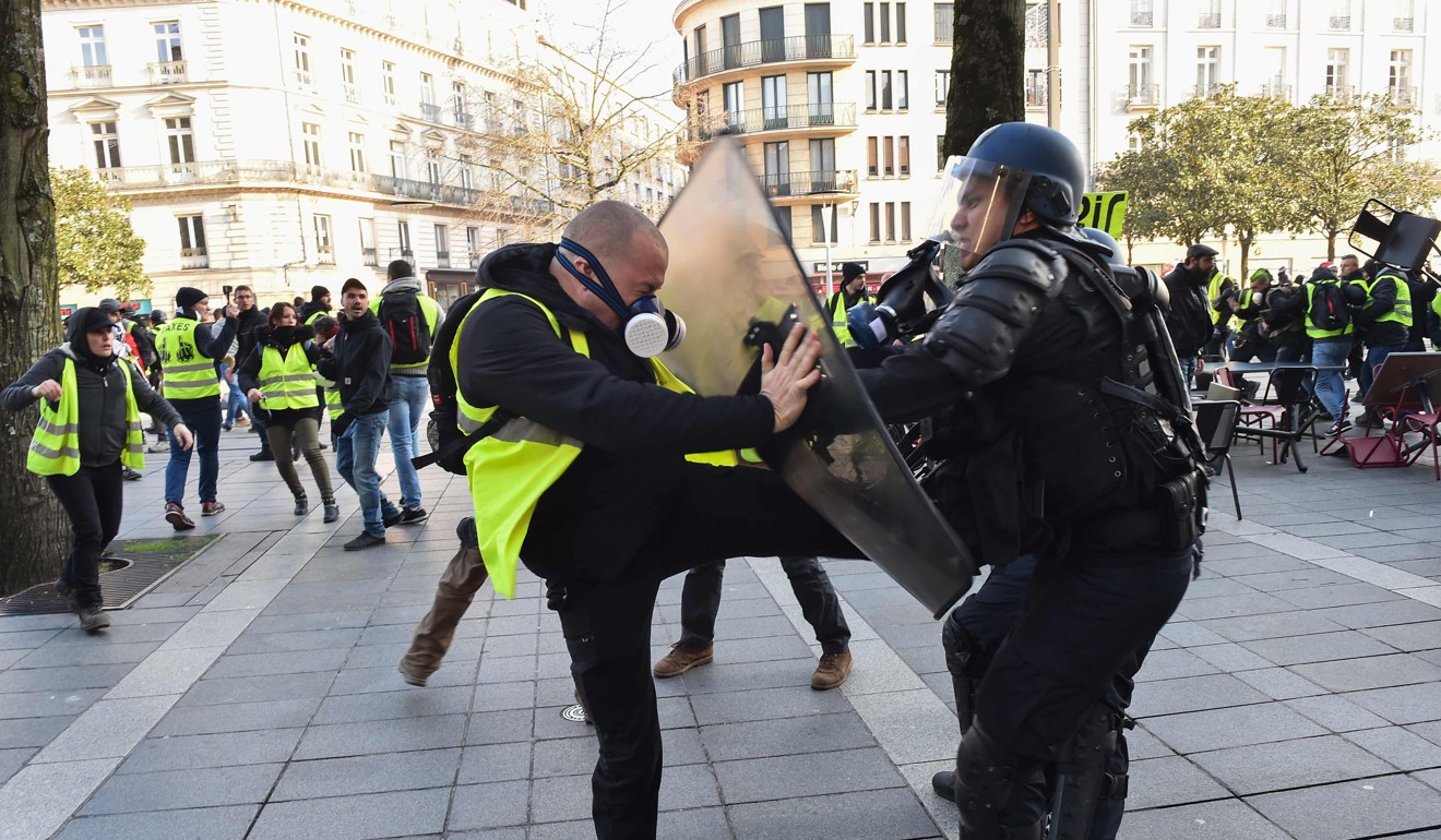 A protester tries to kick a riot policeman in Nantes, western France. Photo: AFP
