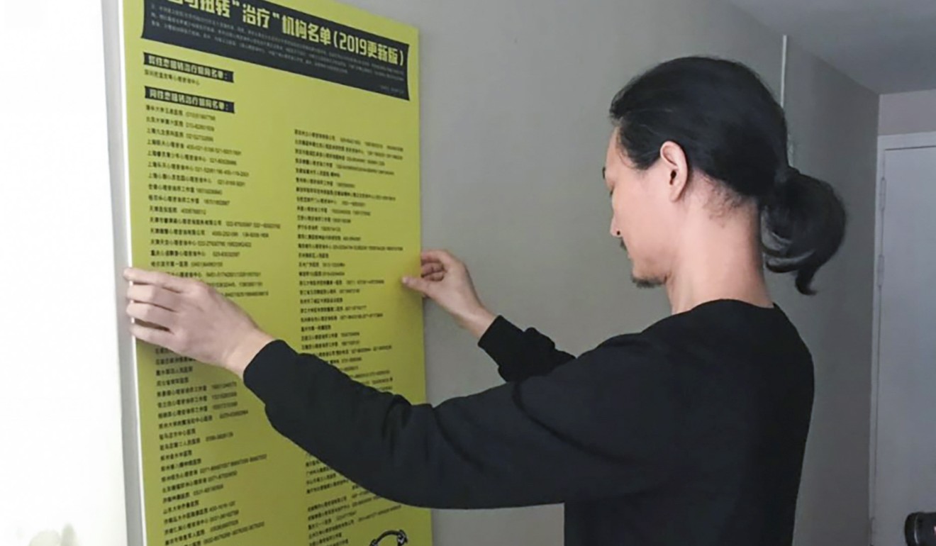 Artist Nut Brother hangs up a sign listing clinics in China that offer gay conversion therapy. Photo: Phoebe Zhang