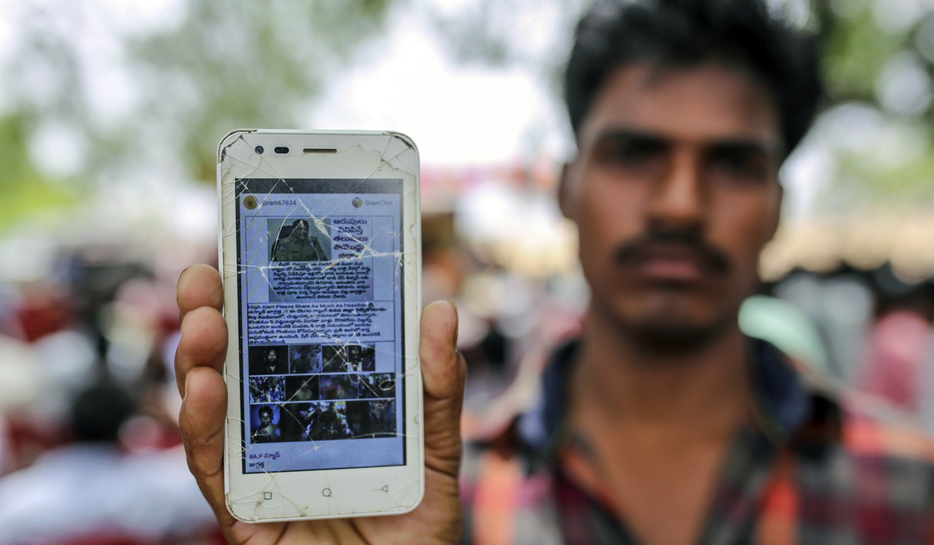 A man holds a mobile phone displaying a fake message shared on Facebook’s WhatsApp messaging service. Photo: Bloomberg