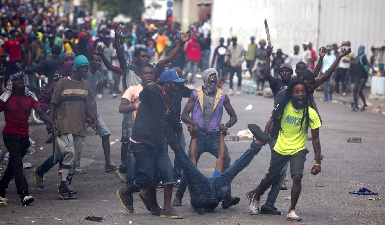 Demonstrators drag the dead body of a fellow protester toward police after they had shot into the crowd. Protesters are calling for the resignation of Haitian President Jovenel Moise. Photo: AP