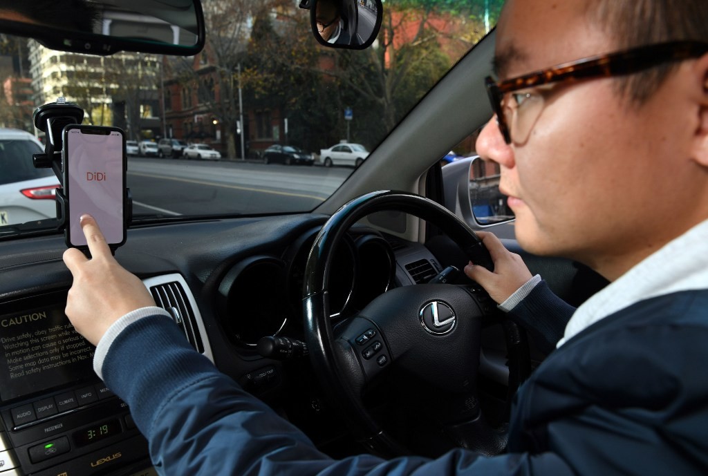 A staffer demonstrates the Didi app on his smartphone in Melbourne, Australia on June 25, 2018. (Picture: AFP Photo)