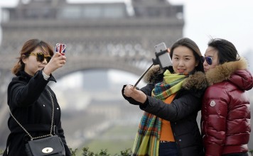 Tourists take selfie near the Eiffel Tower in Paris. Photo: AFP