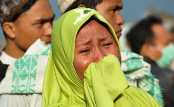A woman cries as people look at the damage in Palu. Photo: AFP