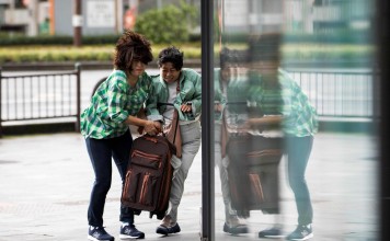 Pedestrians carry a bag as they walk against a strong wind after Typhoon Trami hit the city of Kagoshima on Kyushu island. The storm left four people dead, authorities said. Photo: AFP