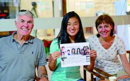 The girl, identified only as Lily and pictured with her parents, holds a leaflet appealing for information about her original family. Photo: Handout