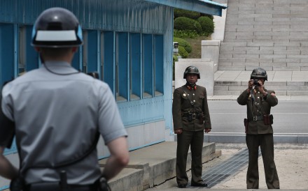 A North Korean soldier takes a photo of a South Korean soldier on guard just behind the military demarcation line. Photo: EPA