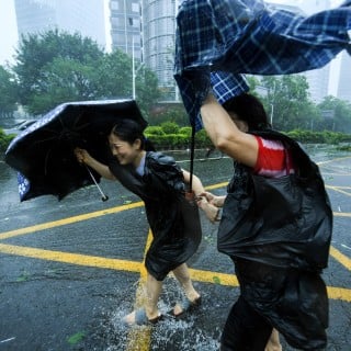 Two residents brave the wind in Shenzhen's Nanshan district on Sunday. Photo: Xinhua