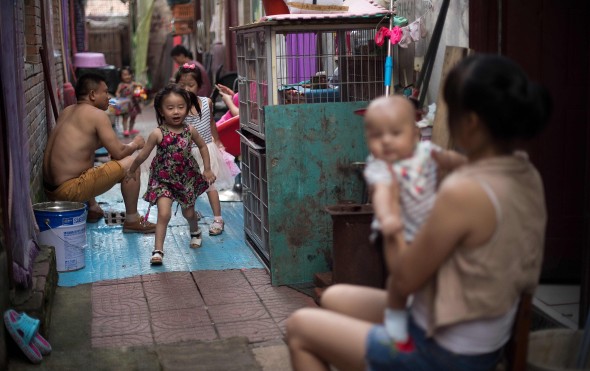 A family sits and plays outside their rooms in a migrant village on the outskirts of Beijing. Photo: AFP A family sits and plays outside their rooms in a migrant village on the outskirts of Beijing. Photo: AFP
