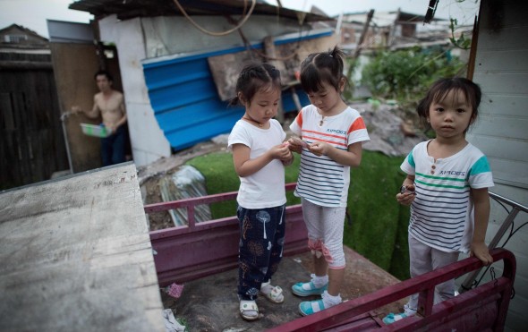 Girls play on the back of a rickshaw in a migrant village. Photo: AFP Girls play on the back of a rickshaw in a migrant village. Photo: AFP