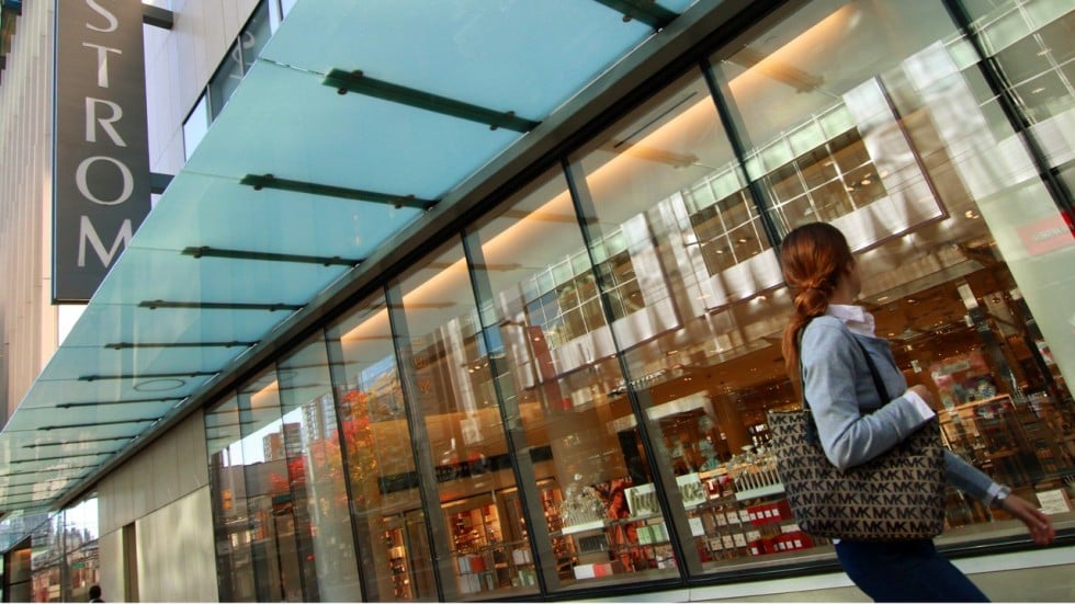 A woman walks pass a Louis Vuitton advertisement in a shopping